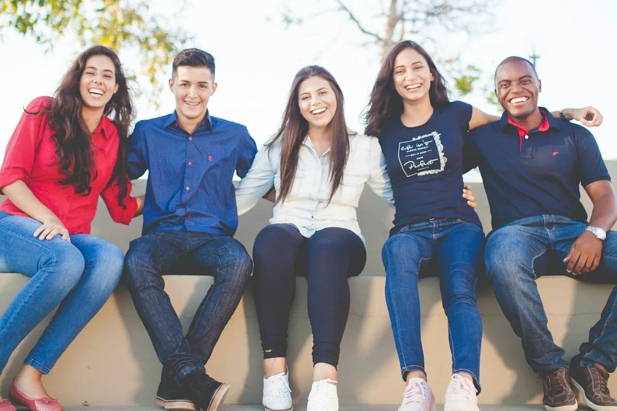 Cinque studenti sorridenti seduti insieme all’aperto