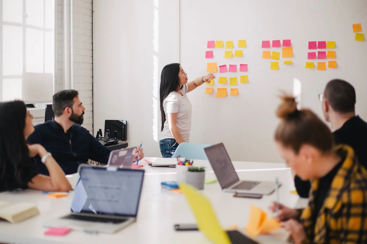 Un gruppo di lavoro discute davanti a una parete di post-it